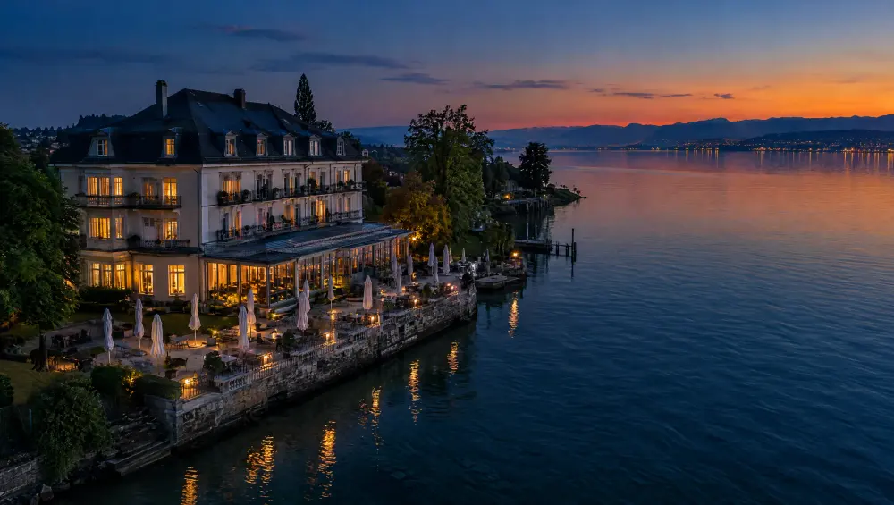 Luftaufnahme eines Hotels mit Seeterrasse am Bodensee zur blauen Stunde