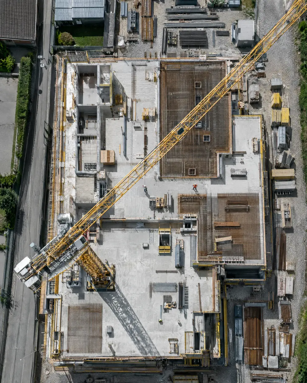 Senkrechte Drohnenaufnahme einer Baustelle im Rohbau mit Kran und Bewehrung